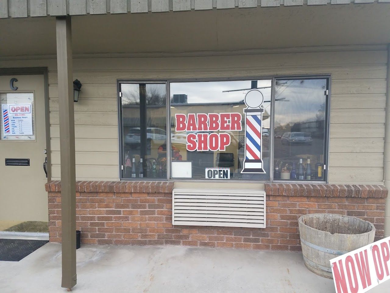 The brick exterior of Garrity Barber Shop with a window sign and barber pole