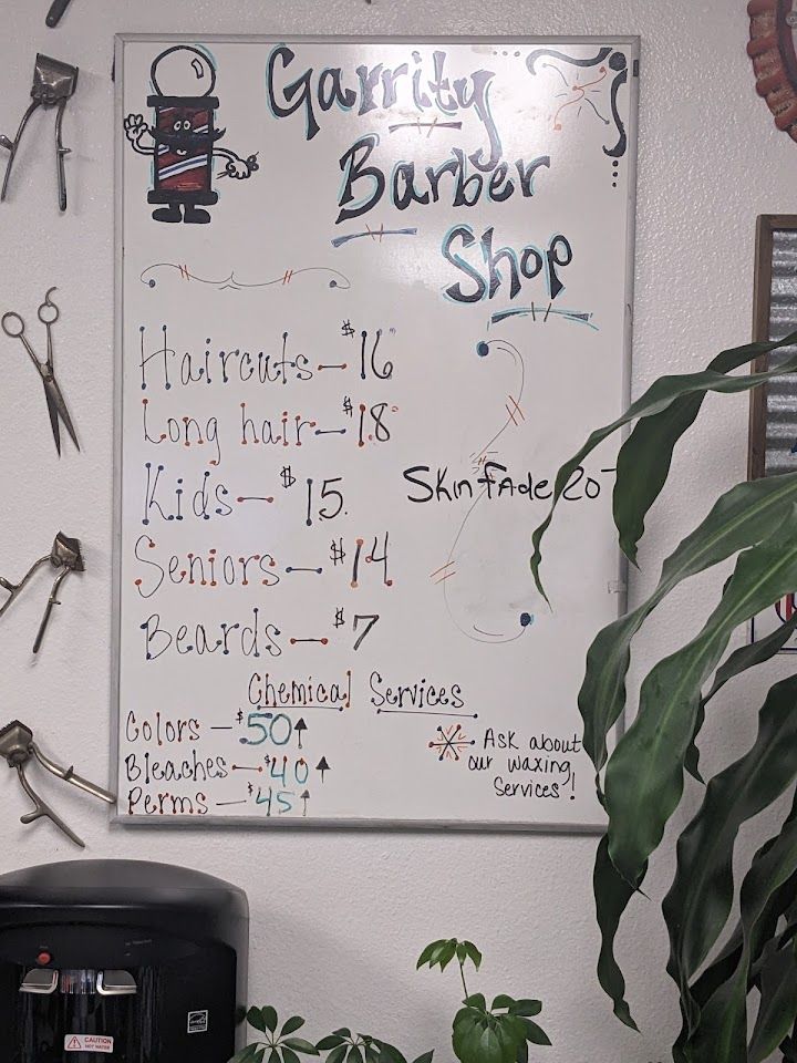 The handwritten price board on the wall at Garrity Barber Shop listing haircut prices